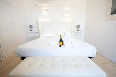 a white bed with a bottle of wine on it at Romerooms Cola di Rienzo in Rome