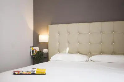 a bedroom with a white bed with a white headboard at Colosseo Prestige Rooms in Rome