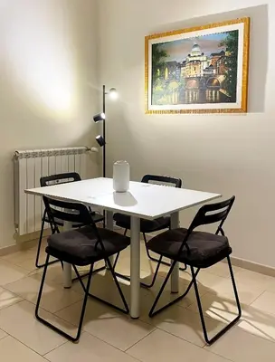 a white table with chairs and a painting on the wall at Studio Flat Vaticano in Rome