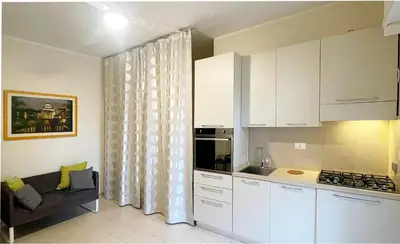 a kitchen with white cabinets and a couch in a room at Studio Flat Vaticano in Rome