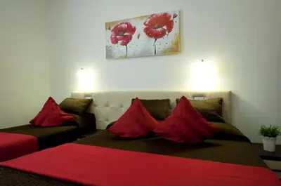 a bedroom with a bed and a couch with red pillows at Ara Pacis Inn in Rome