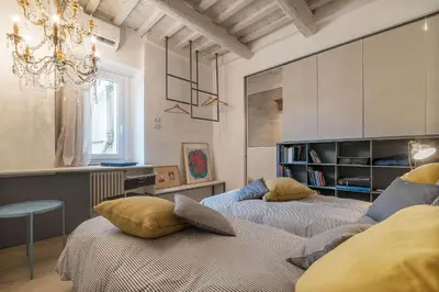 two beds in a room with a chandelier at GuestHost - Piazza Venezia&Colosseum Loft in Rome