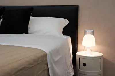 a bedroom with a bed with a lamp on a night stand at Roma Naif Rooms in Rome