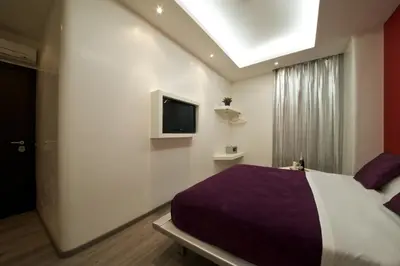 a bedroom with a bed and a tv on the wall at Roma Naif Rooms in Rome