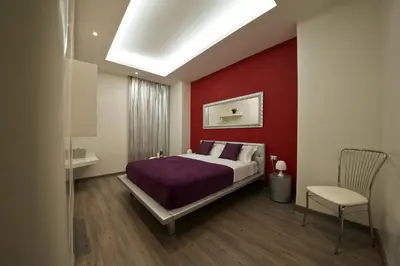 a bedroom with a bed and a red wall at Roma Naif Rooms in Rome