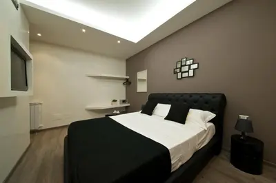 a bedroom with a large bed with a black headboard at Roma Naif Rooms in Rome