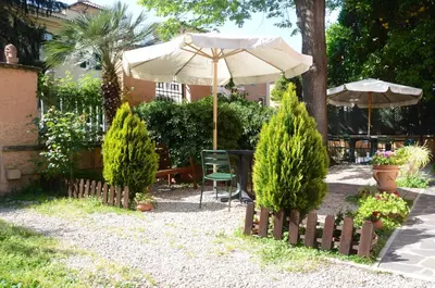 a garden with an umbrella and a table and chairs at A Vinicius et Mita in Rome