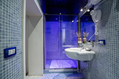 a blue tiled bathroom with a sink and a shower at Town House Campo De Fiori in Rome