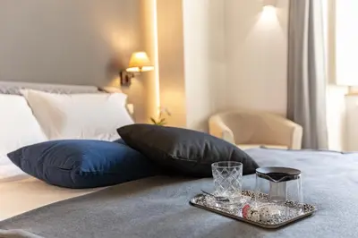 a tray with a glass on a bed with pillows at Lombardia40 Luxury Suites in Rome