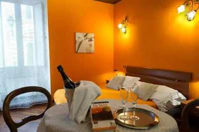 a bedroom with a bed and a table with a wine bottle at GREGORIANA HOUSE - Appartamento con Vista su Roma in Rome