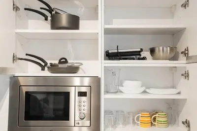 a kitchen with a microwave and shelves with dishes at Casette Romane 