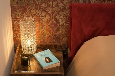 a bedside table with a lamp and a book on it at GuestART Monti Apartment in Rome