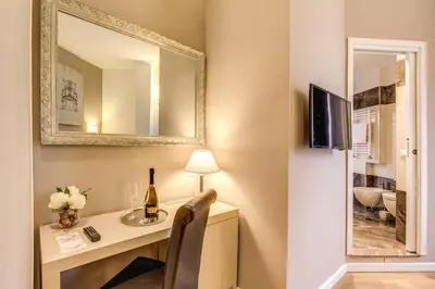 a room with a desk with a bottle of wine and a mirror at The Bridge Suites in Rome