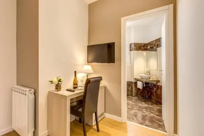 a room with a desk with a chair and a bathroom at The Bridge Suites in Rome