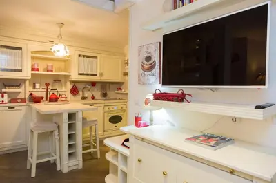 a kitchen with white cabinets and a large tv on the wall at Pantheon Romantic Loft in Rome