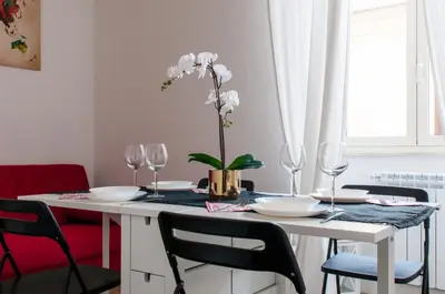 a white table with glasses and a vase with white flowers at St. Peter Vatican Apartment in Rome