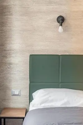 a bedroom with a bed with a green headboard and a light at Luciano Licia Guest House in Rome