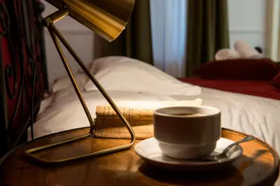 a cup of coffee on a table with a lamp at Colosseum B in Rome