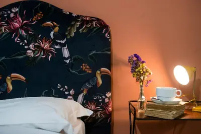 a bed with a floral head board with a table with flowers at Colosseum B in Rome