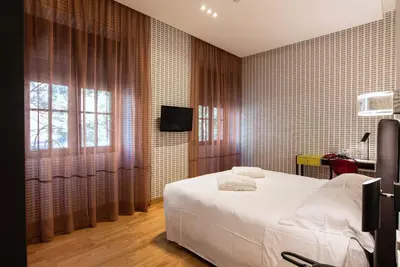 a bedroom with a white bed and a tv at Albergo Etico Roma in Rome