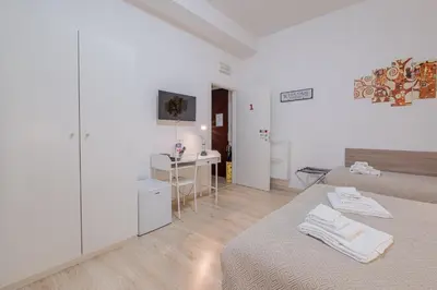 a white room with two beds and a desk at Damiani & Sister Guesthouse in Rome