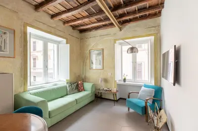 a living room with a green couch and two windows at iFlat Vatican High-End Apartment in Rome