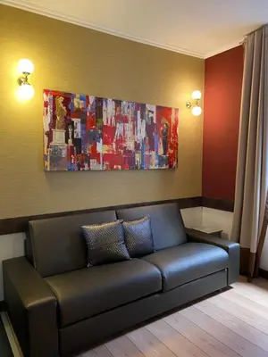 a couch in a living room with a painting on the wall at HiSuiteROME - ApartHotel in Rome