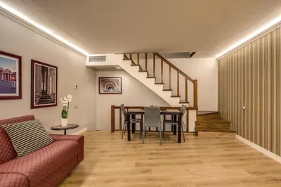 a living room with a table and a staircase at HiSuiteROME - ApartHotel in Rome