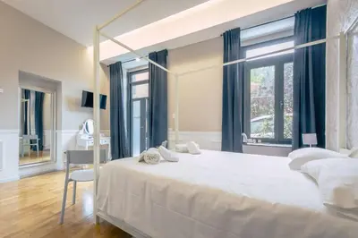 a bedroom with a large white bed and a desk at Trastevere Glasshouse in Rome