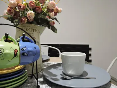 a table with plates and a cup and a vase with flowers at Domus Angelica in Rome