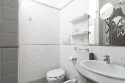 a white bathroom with a toilet and a sink at White Caesar Guesthouse in Rome