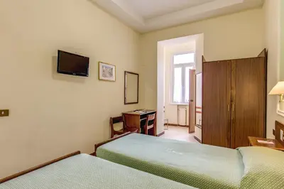 a bedroom with two beds and a tv on the wall at Hotel Igea in Rome