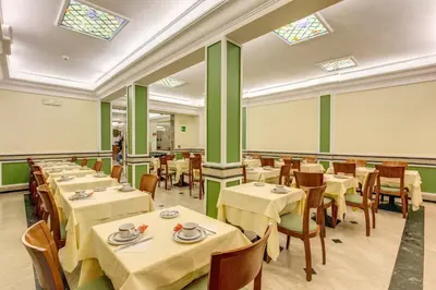 a dining room with tables and chairs and windows at Hotel Igea in Rome