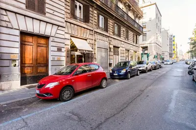 a red car parked on the side of a city street at Elegant Apartment Rome in Rome
