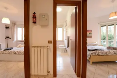 a room with two beds and a hallway with a bathroom at GiuMa Roma Vatican Apartment in Rome