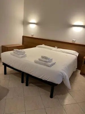a bed with white sheets and towels on it at La Casa di Nazareth in Rome