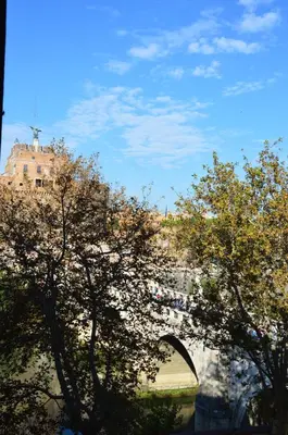 a bridge over a river with trees in the foreground at Una finestra su Castel Sant'Angelo in Rome