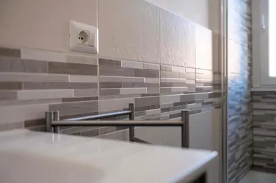 a bathroom with a white counter and a tile wall at Lo Sguardo sui Re in Rome