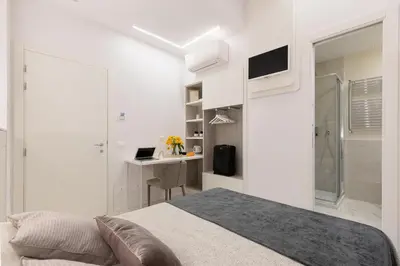 a white bedroom with a bed and a desk at Cavour Suites Guest House in Rome