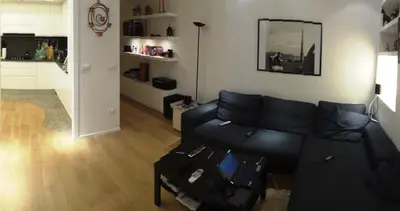 a living room with a black couch and a kitchen at Urbanflat Roma in Rome
