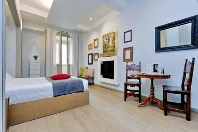 a bedroom with a bed and a table and a television at Raffaello Charmsuite in Rome