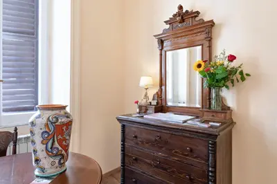 a dresser with a mirror and a vase with flowers on it at Vatican Domus Luxury Rooms in Rome