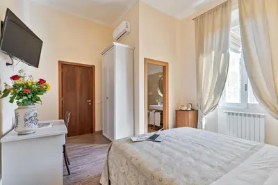 a bedroom with a bed with a vase of flowers at Vatican Domus Luxury Rooms in Rome