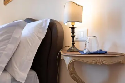 a lamp on a side table next to a bed at Vatican Domus Luxury Rooms in Rome