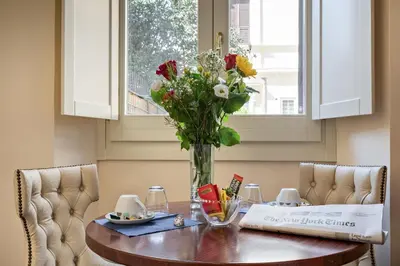 a vase of flowers on a table with two chairs at Vatican Domus Smart Rooms in Rome