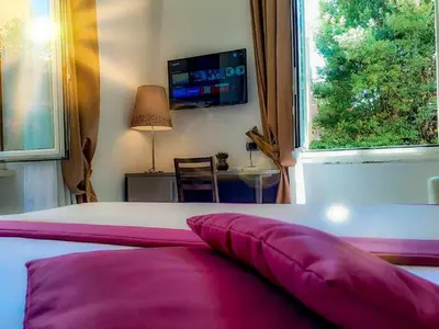 a bedroom with a bed with pink pillows and a tv at Aventino Guest House in Rome
