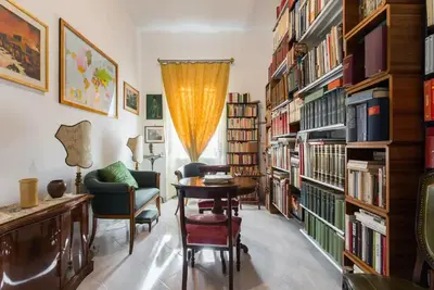 a library with a table and chairs and bookshelves at Casa Vacanze Casilina in Rome