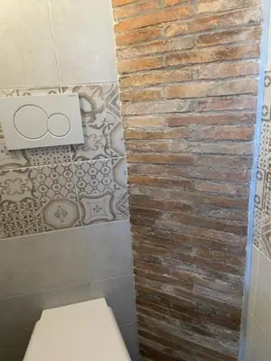 a bathroom with a toilet and a brick wall at Casa Vacanze Casilina in Rome