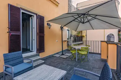 a patio with a table and chairs and an umbrella at President Gardens in Rome