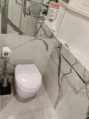 a white toilet in a bathroom with marble walls at La Calla al Colosseo in Rome